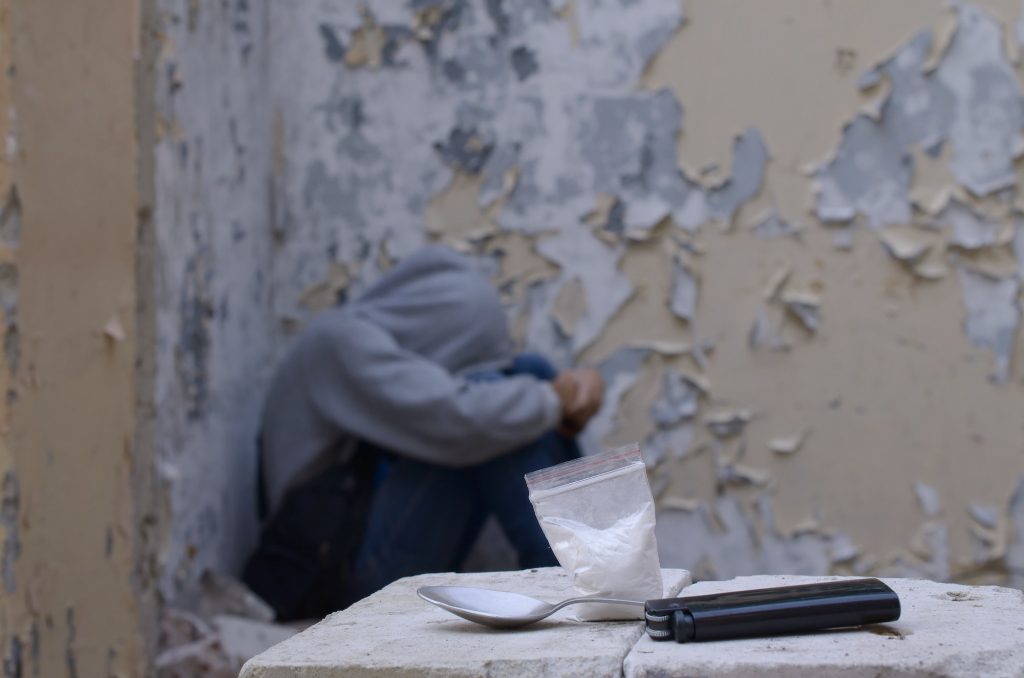 A drug-dependent man suffers from drug withdrawal while sitting in abandoned building next to dose