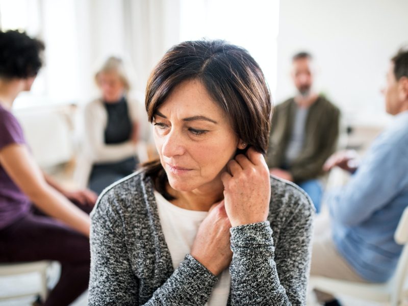 Portrait of senior depressed woman during group therapy.