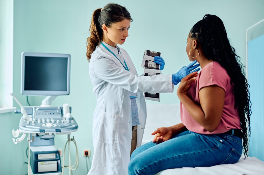 Female doctor examining black woman's neck during medical appointment at the clinic.