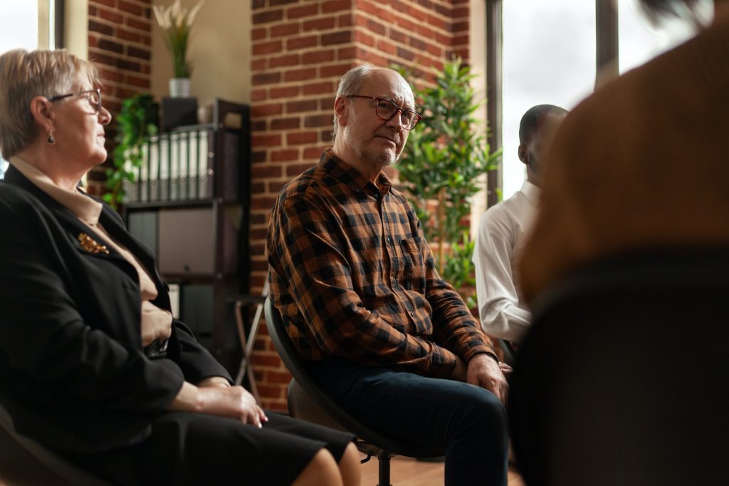 People talking to therapist at aa group therapy meeting, sharing addiction problems